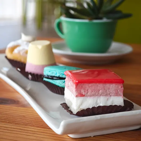 Pasticcini su un vassoio, con una tazza verde sullo sfondo