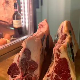 Due tagli di manzo con l'osso davanti alla vetrina della frollatura
