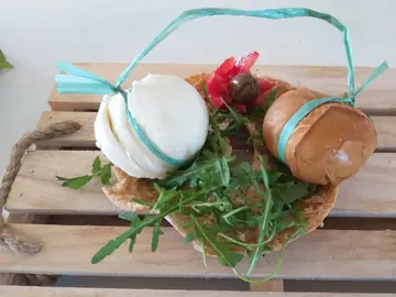 Mozzarella e scamorza affumicata in un cestino di pane, con rucola e olive