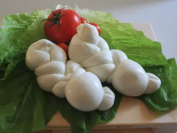 Una treccia di mozzarella su foglie di lattuga, con un pomodoro