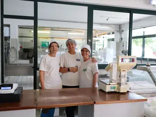 Tre casare in divisa bianca dietro il banco del punto vendita