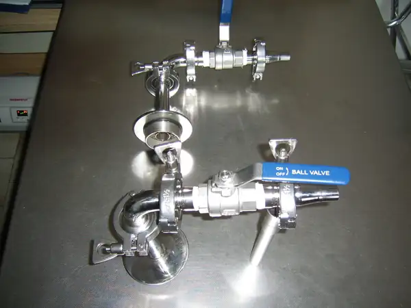 Raccordi e valvole a sfera in acciaio inox appoggiati su un banco