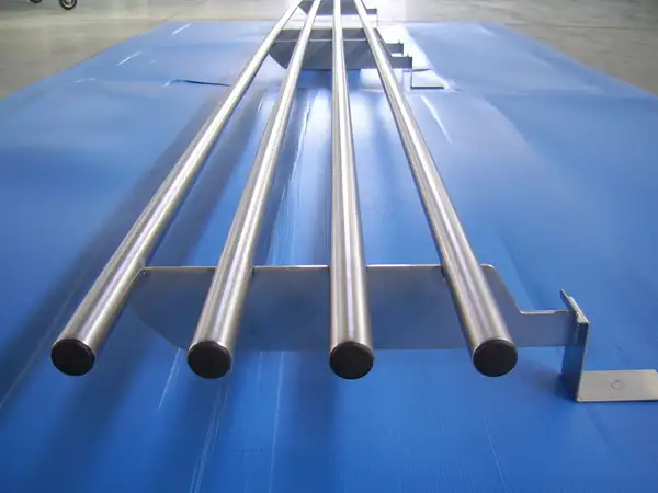 Barre tonde in acciaio inox saldate a una staffa, su un telo blu