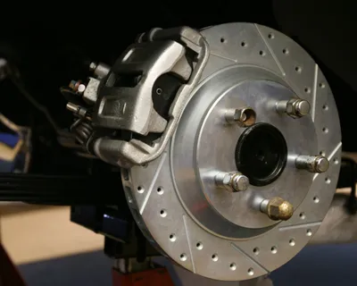 Il disco forato e la pinza del freno di un'auto sui cavalletti, con la ruota smontata
