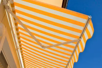 Una tenda da sole a righe gialle e bianche contro il cielo azzurro