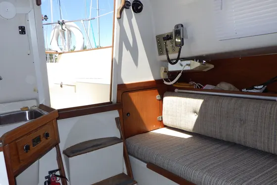 Interno di una barca a vela con i mobili in legno, il divanetto e la scaletta verso il pozzetto