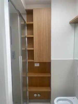 Colonna di mensole in legno chiaro accanto alla doccia