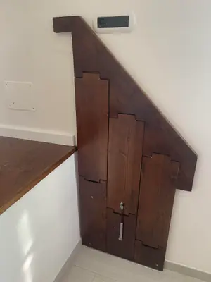 Pannello in legno scuro sagomato a gradini che chiude il sottoscala
