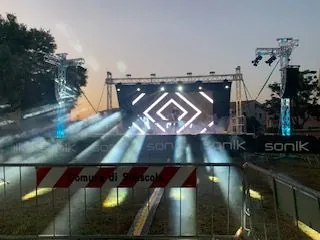Palco al tramonto con fasci di luce bianca e una cornice LED al centro