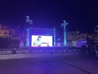 Uno schermo LED appeso al traliccio di un palco, di notte