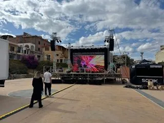 Palco con lo schermo LED in una piazza, sotto un cielo di nuvole