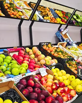 Il banco della frutta: mele verdi, gialle e rosse, pesche e agrumi nelle cassette