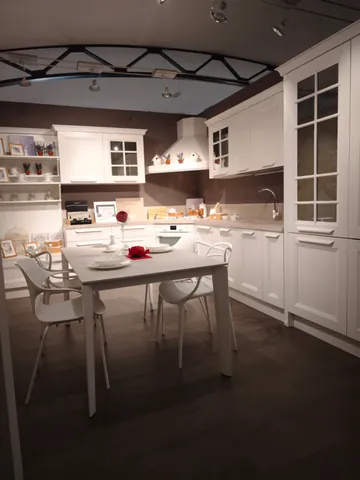 Cucina classica bianca con vetrine, tavolo e sedie bianche apparecchiati
