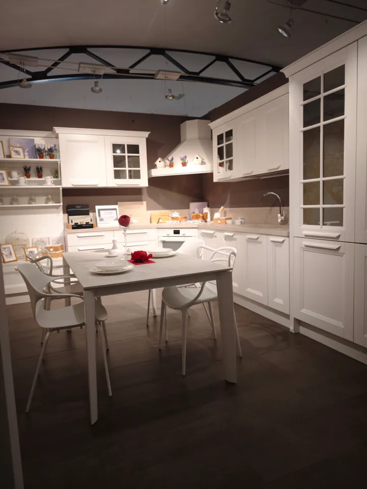 Cucina classica bianca con vetrine, tavolo e sedie bianche apparecchiati