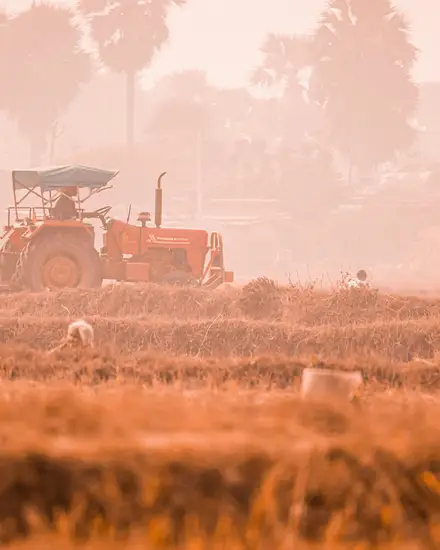 Un trattore al lavoro in un campo, nella foschia