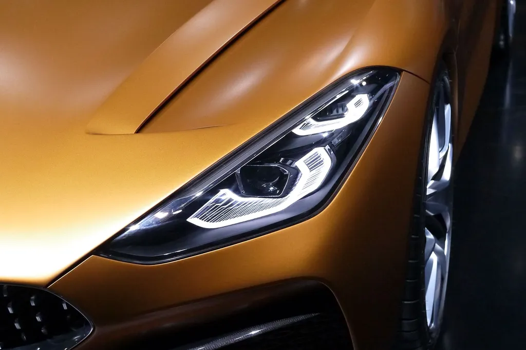 Il faro anteriore acceso di una sportiva color oro, con le linee di luce a LED