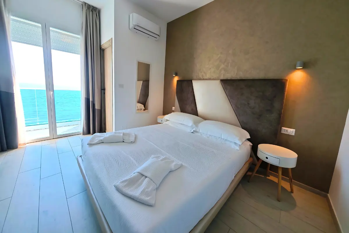 Una camera dell’Hotel Tirreno: il letto matrimoniale e, oltre la portafinestra, il mare