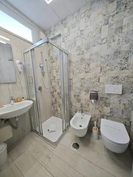 Il bagno di una camera, con la doccia in cristallo e le piastrelle decorate