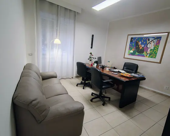 Uno degli uffici dell'agenzia: il divano grigio, la scrivania e un quadro colorato