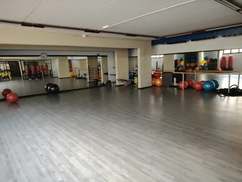 La sala vuota e luminosa, con la sbarra, le palle colorate e i sacchi lungo gli specchi