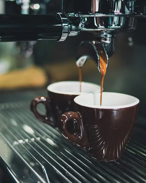 La macchina dell'espresso che versa il caffè in due tazzine