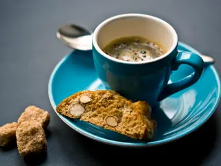 Un espresso nella tazzina azzurra, con i cantucci sul piattino