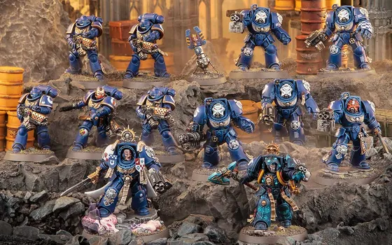 Una squadra di Terminator e Space Marine Ultramarines di Warhammer 40.000, dipinti di blu, su un plastico di rocce con barili arancioni