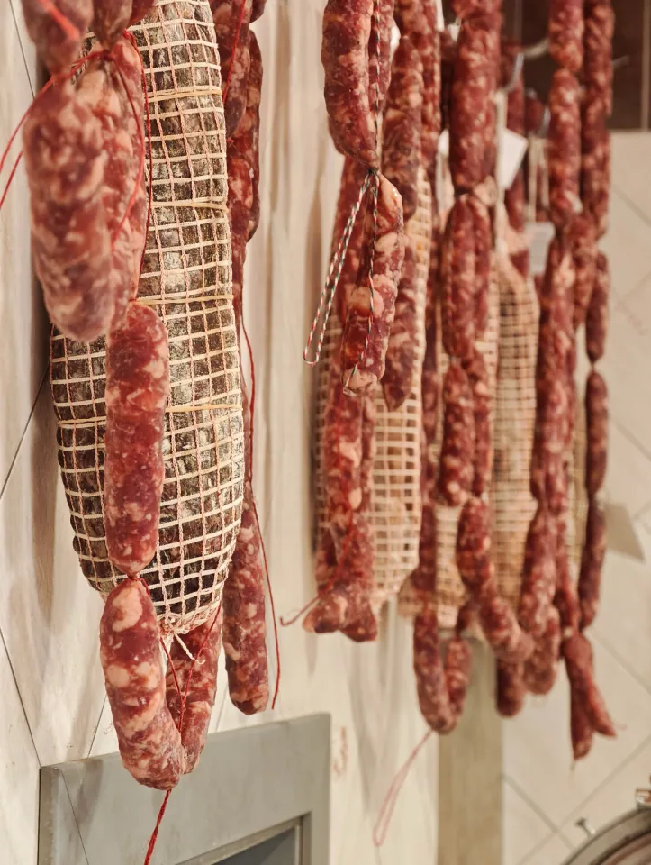 Salami legati con rete appesi a stagionare al muro