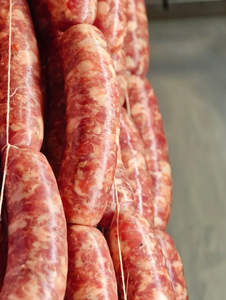 Salsicce fresche legate a catena appese in fila
