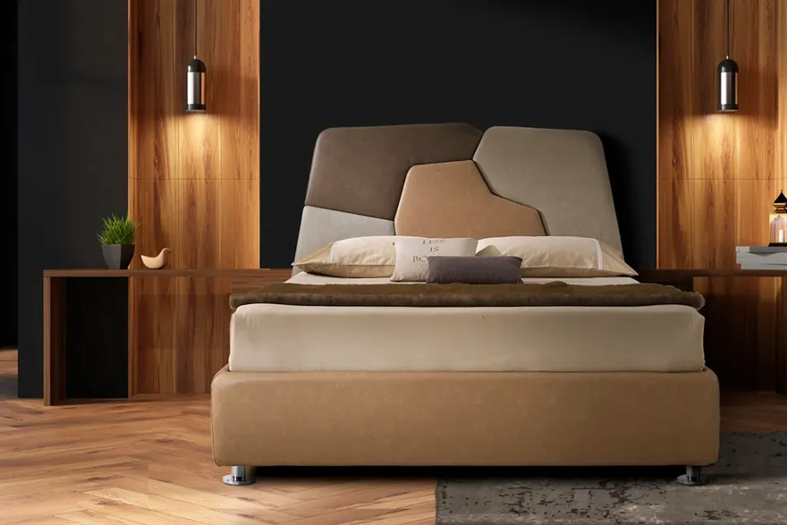 Letto Artigianaletti con la testiera a intarsi di tessuti beige e tortora, fra pannelli di legno e due lampade sospese