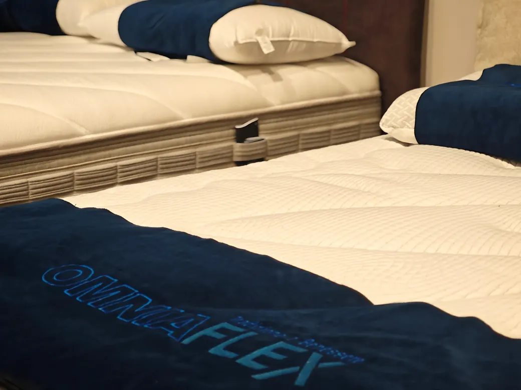 Due letti nel negozio, con la fascia blu ricamata «Omniaflex» sul materasso