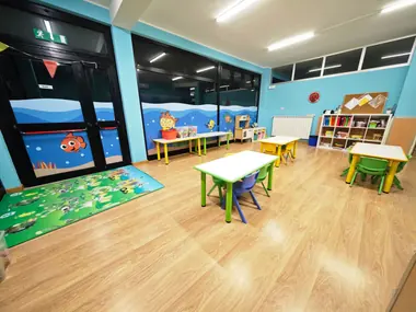 L'aula Dori: tavoli e sedie verdi, il tappeto e le vetrate con Nemo e il mare