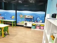 L'aula Dori con la cucina giocattolo e i contenitori colorati sotto il mare dipinto