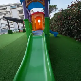 Uno scivolo verde con la sua casetta colorata, nel giardino