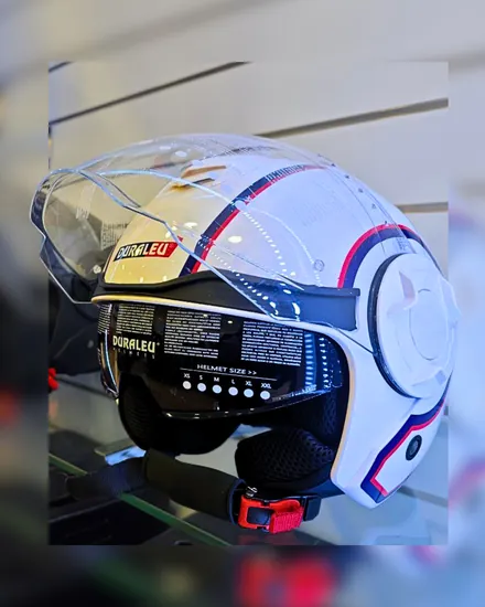 Un casco jet bianco con la visiera trasparente, esposto su una mensola di vetro