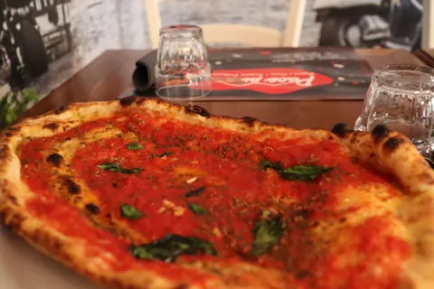 Una pizza al pomodoro con origano e basilico, vista da vicino