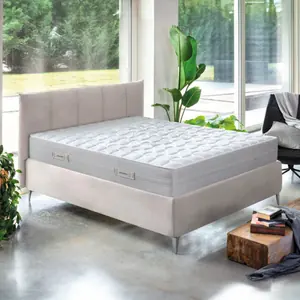 Letto con testiera imbottita color tortora accanto a una vetrata