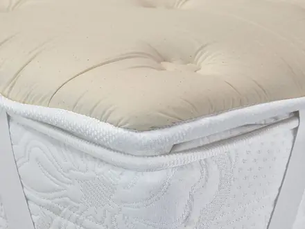 Topper imbottito color panna appoggiato su un materasso