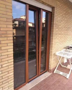 Portafinestra a due ante effetto legno su un balcone in mattoni