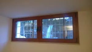 Finestra a due ante effetto legno vista dall'interno, con la grata oltre il vetro