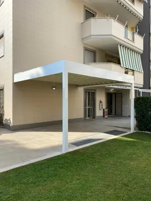 Pergola bianca sul prato, sotto un palazzo con i balconi