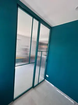 Parete vetrata con telaio sottile verde petrolio e vetro cannettato