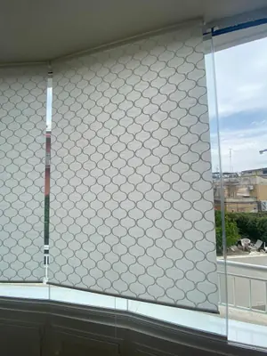 Tenda tecnica a rullo con motivo a squame dietro una vetrata panoramica