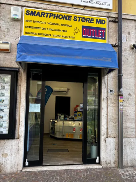 L'ingresso dell'Outlet al civico 115, con l'insegna gialla «Smartphone Store MD Outlet» e la tenda blu