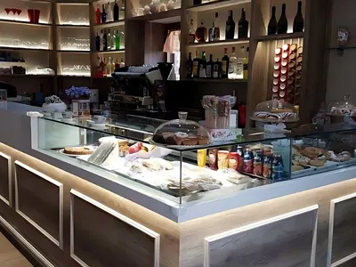 Bancone di un bar con vetrine refrigerate e luci sotto il piano, allestito da Spaziani Arreda