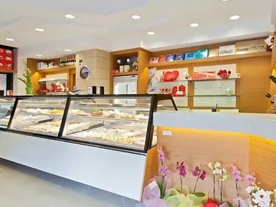 Pasticceria con vetrine per i dolci e mobili in legno chiaro: un lavoro di Spaziani Arreda