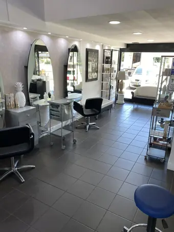 Il salone vuoto, con le poltrone nere, le specchiere ad arco e il carrello