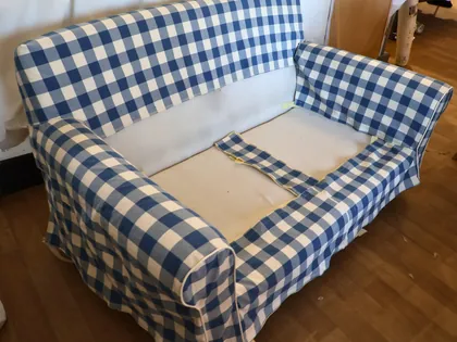 Un divano in lavorazione, con il rivestimento a quadri bianchi e blu in parte smontato
