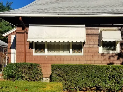 Due tende da sole bianche con la mantovana ondulata sopra le finestre di una casa