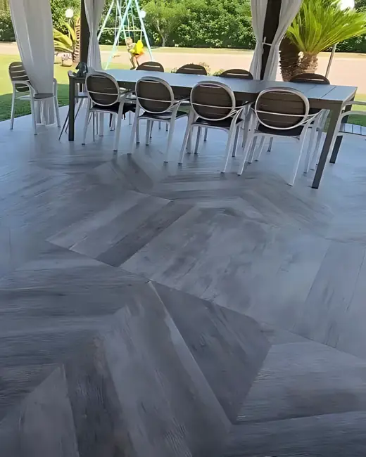 Pavimento effetto legno grigio posato a spina di pesce sotto un gazebo, con tavolo e sedie